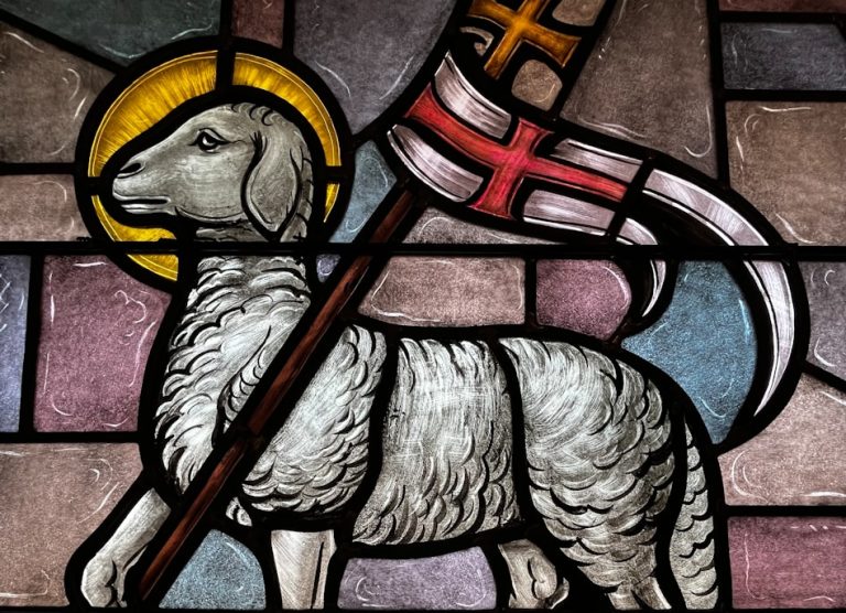 a stained glass window with a sheep holding a flag